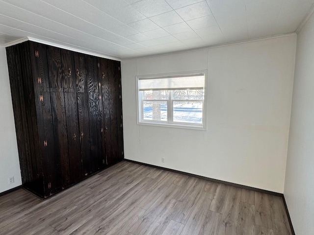 unfurnished bedroom featuring crown molding, light wood-type flooring, and a closet