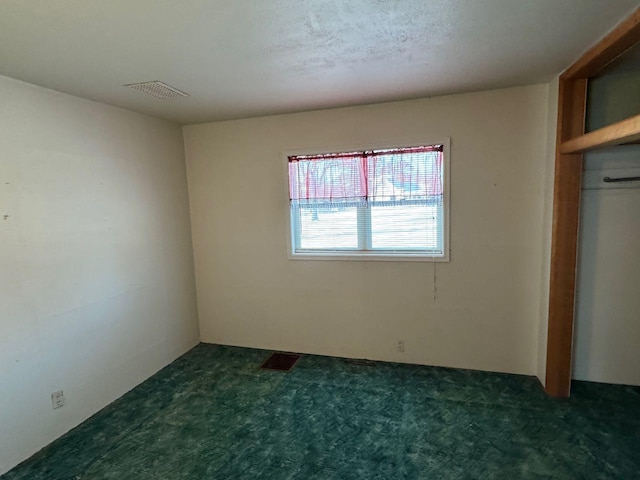 unfurnished bedroom with dark carpet, a closet, and a textured ceiling