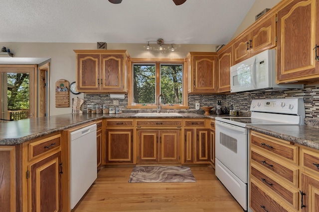 kitchen with kitchen peninsula, light wood-type flooring, white appliances, and sink