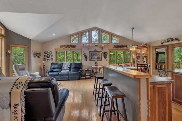 living room with a textured ceiling, vaulted ceiling, light hardwood / wood-style flooring, and ceiling fan