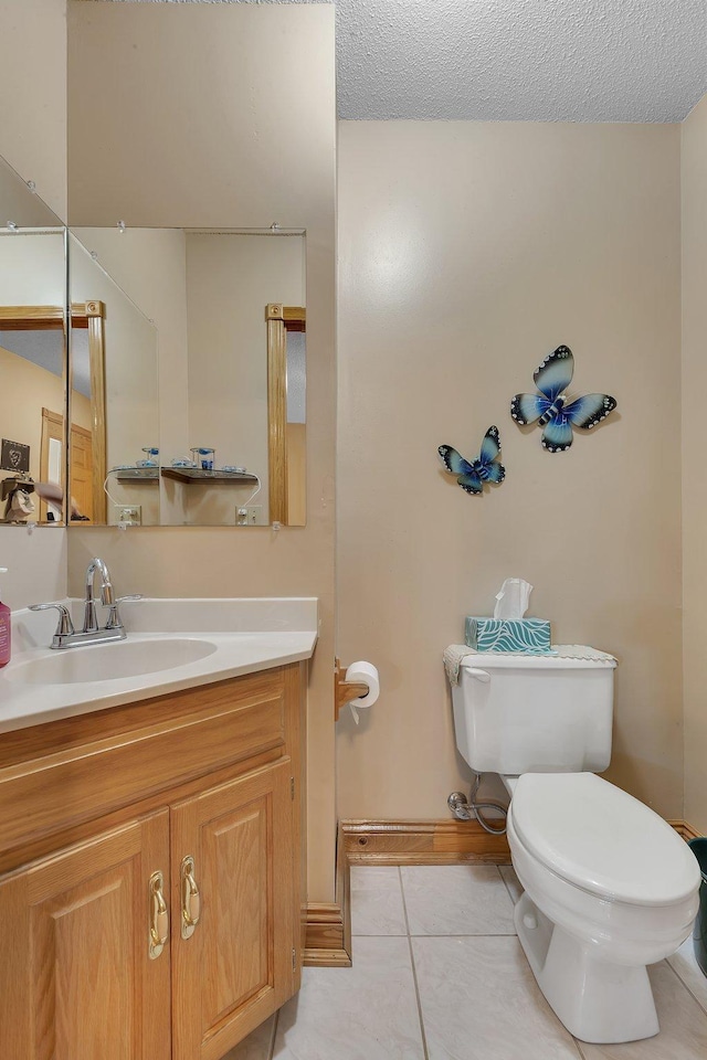 bathroom featuring tile patterned flooring, vanity, a textured ceiling, and toilet