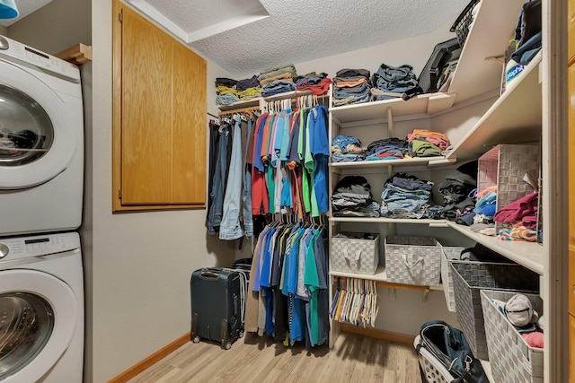 laundry area featuring a textured ceiling, light hardwood / wood-style floors, and stacked washer and clothes dryer