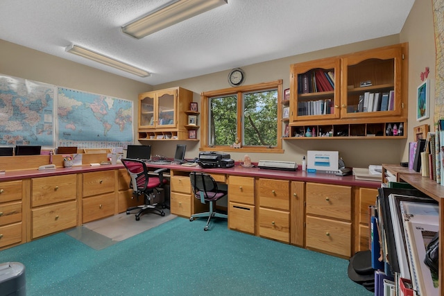 office space featuring light carpet, a textured ceiling, and built in desk