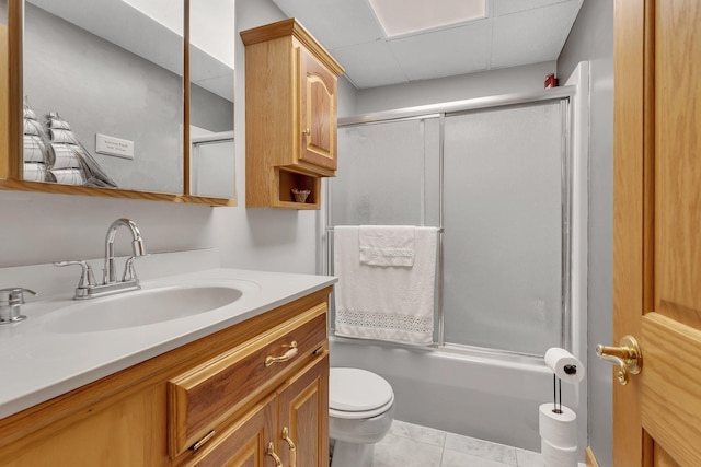 full bathroom featuring enclosed tub / shower combo, tile patterned floors, toilet, a paneled ceiling, and vanity