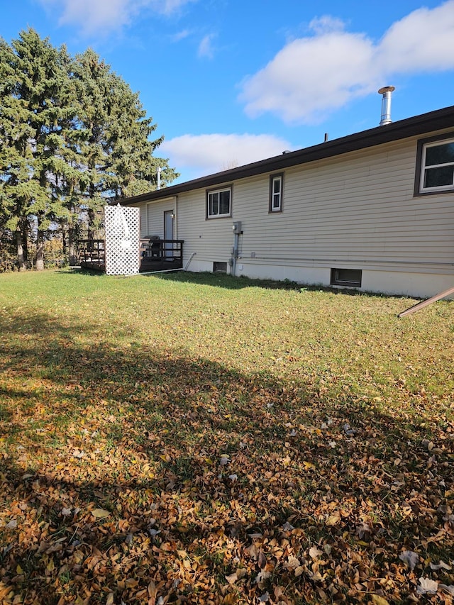 rear view of house featuring a wooden deck and a lawn