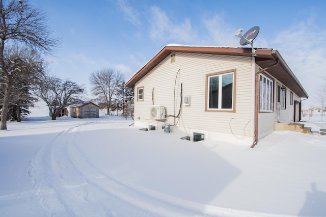 view of snow covered exterior with ac unit and an outbuilding