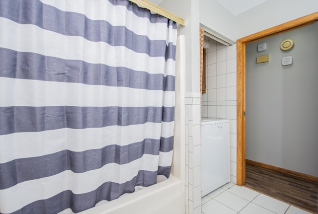 bathroom with tile patterned floors, shower / bath combo with shower curtain, and tile walls