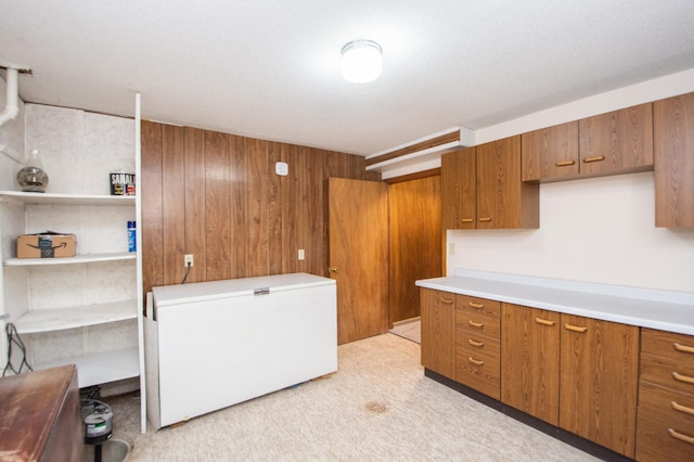 kitchen with a textured ceiling, fridge, and wood walls