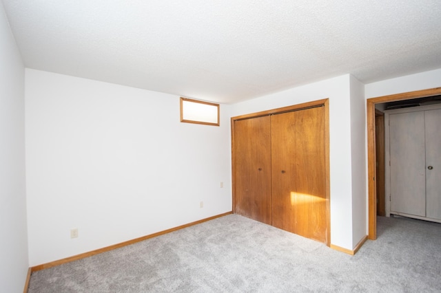 unfurnished bedroom with a textured ceiling, light carpet, and a closet