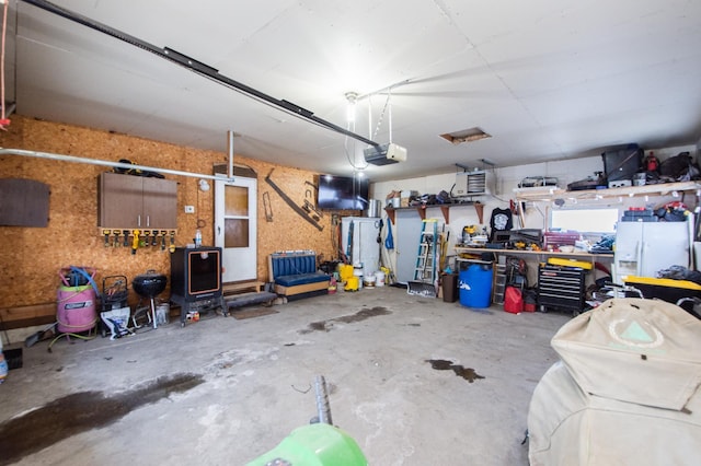 garage featuring a workshop area, a garage door opener, and white fridge with ice dispenser