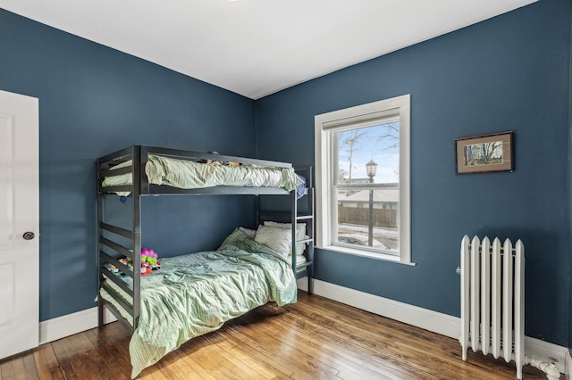 bedroom with radiator and hardwood / wood-style floors