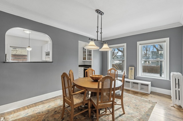 dining space featuring radiator, hardwood / wood-style flooring, baseboards, and crown molding