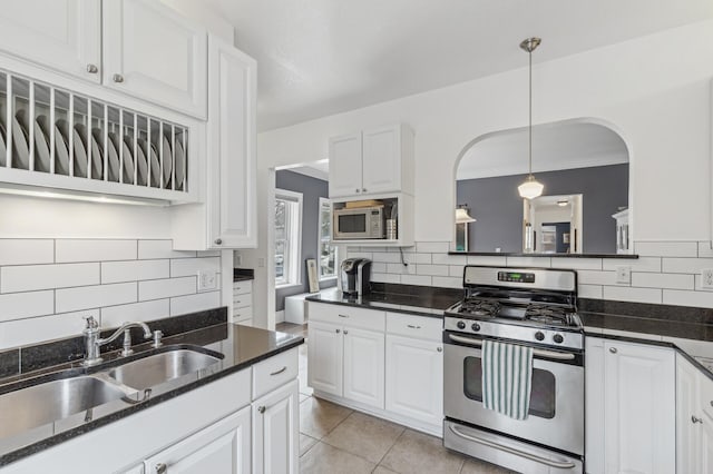 kitchen featuring light tile patterned flooring, a sink, stainless steel gas range oven, and white cabinetry