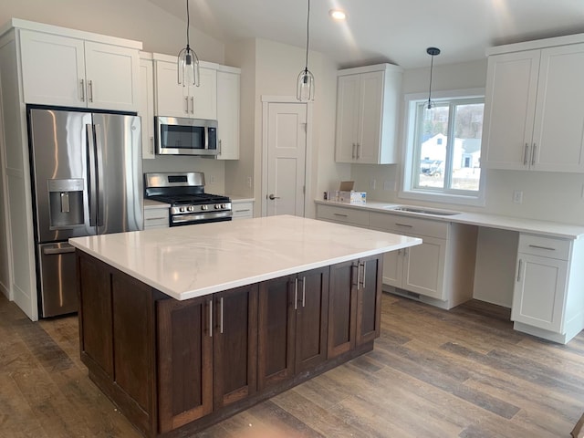 kitchen with appliances with stainless steel finishes, dark hardwood / wood-style flooring, a center island, and white cabinets