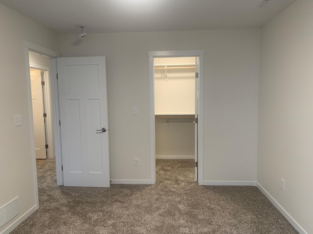 unfurnished bedroom with a spacious closet, carpet floors, and a closet