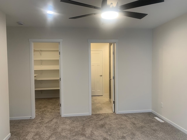 unfurnished bedroom with ceiling fan, a spacious closet, a closet, and light carpet