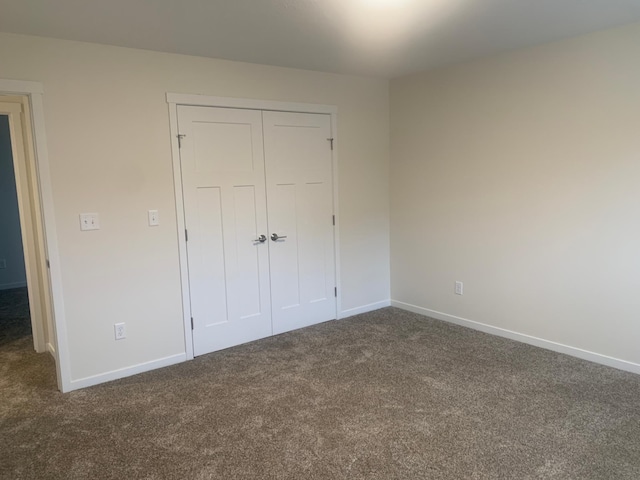 unfurnished bedroom with a closet and dark colored carpet