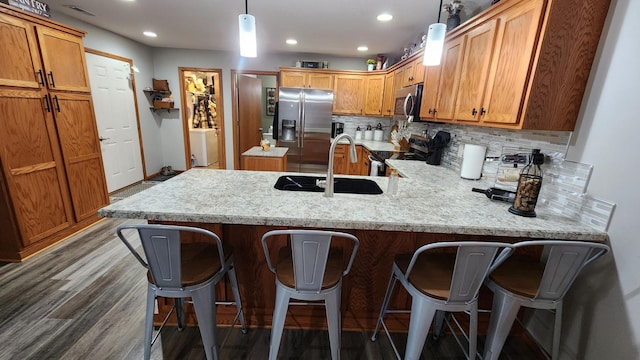 kitchen featuring hardwood / wood-style floors, sink, decorative light fixtures, kitchen peninsula, and stainless steel appliances