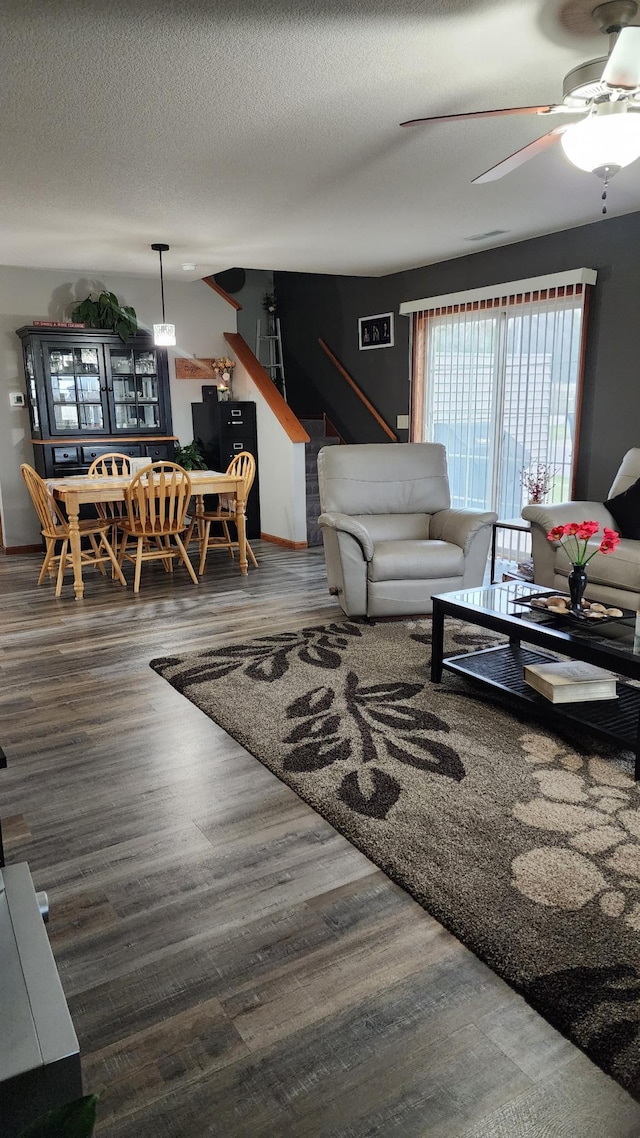 living room with a textured ceiling, dark hardwood / wood-style floors, and ceiling fan