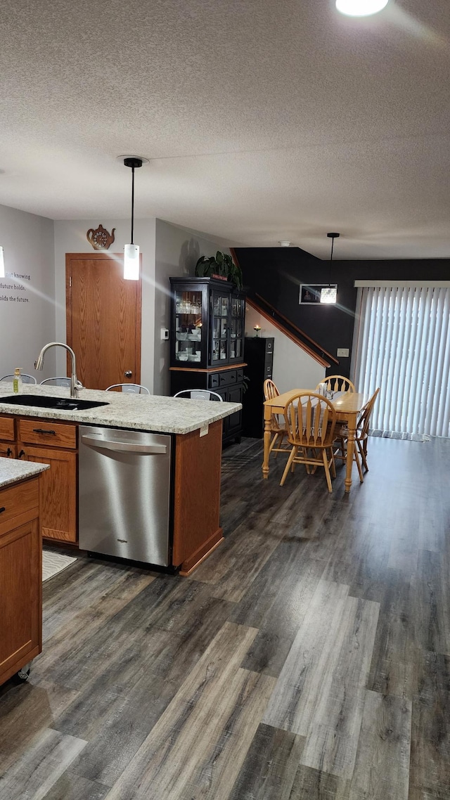 kitchen featuring sink, dark wood-type flooring, stainless steel dishwasher, a textured ceiling, and decorative light fixtures