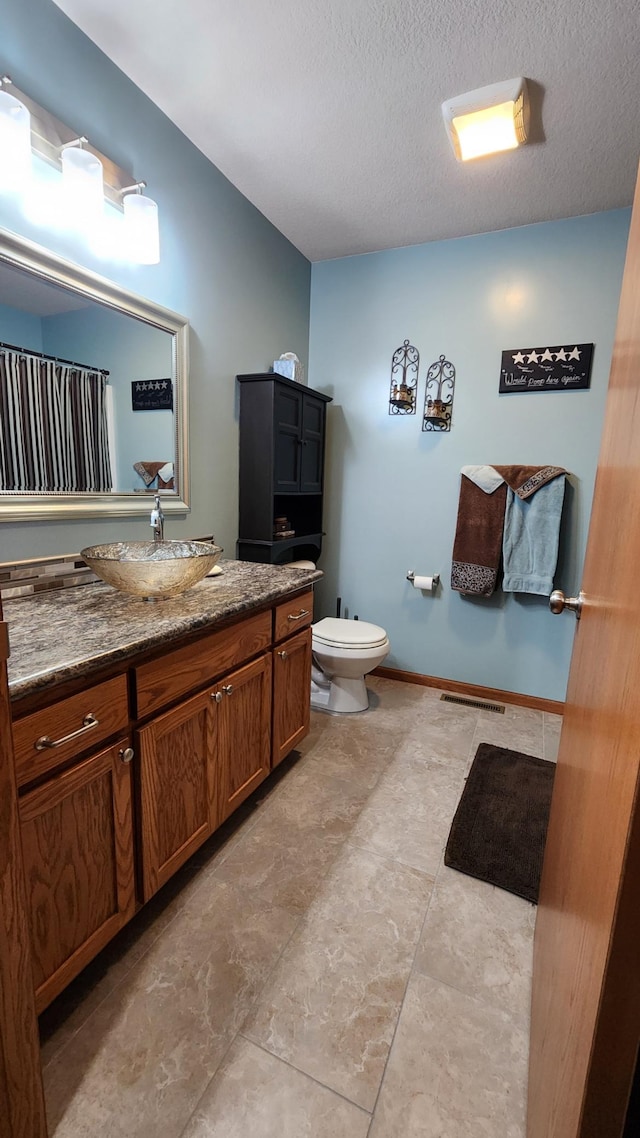 bathroom featuring vanity, toilet, and a textured ceiling