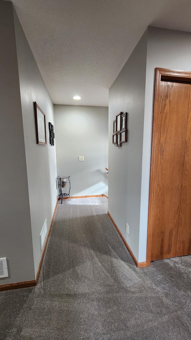 hallway featuring carpet and a textured ceiling