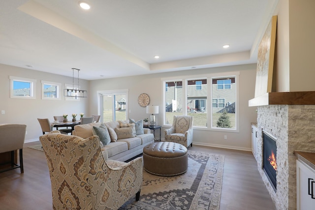 living room with a raised ceiling, a fireplace, and hardwood / wood-style flooring