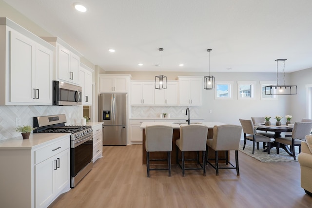 kitchen featuring white cabinetry, hanging light fixtures, and appliances with stainless steel finishes