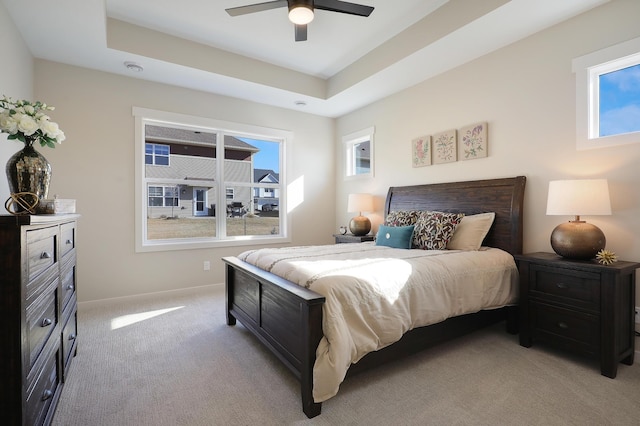 bedroom featuring light carpet, a raised ceiling, and ceiling fan