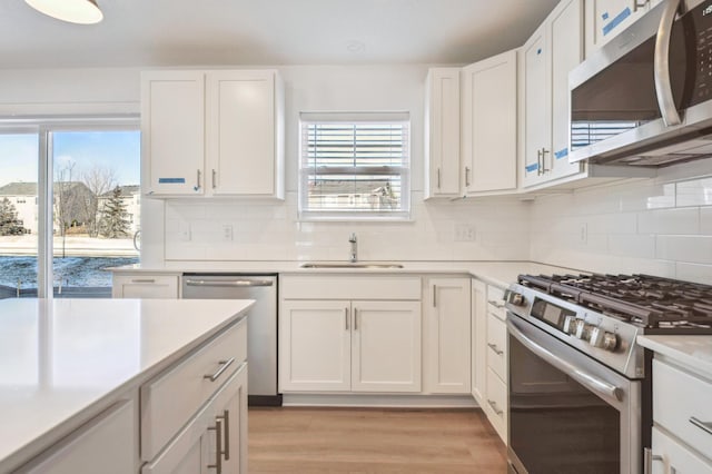 kitchen with stainless steel appliances, sink, a wealth of natural light, and white cabinets