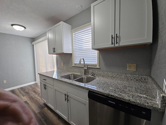 kitchen with light stone counters, stainless steel dishwasher, a textured ceiling, white cabinetry, and sink