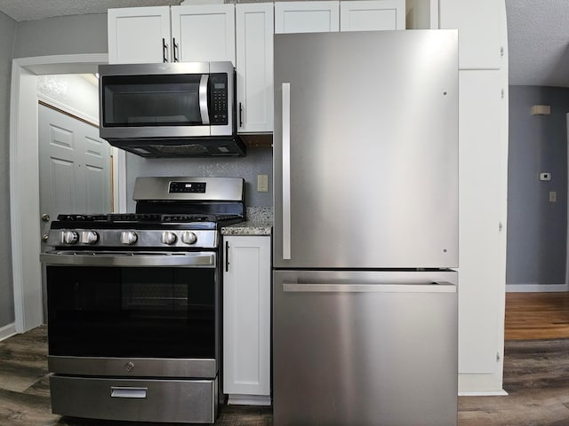 kitchen with a textured ceiling, stainless steel appliances, white cabinetry, and dark wood-type flooring