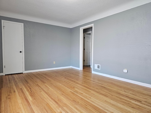 unfurnished room featuring a textured ceiling and light hardwood / wood-style flooring