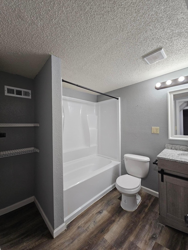 full bathroom featuring shower / washtub combination, hardwood / wood-style floors, toilet, vanity, and a textured ceiling