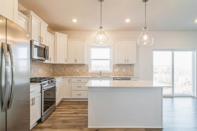 kitchen featuring white cabinets, a kitchen island, pendant lighting, and appliances with stainless steel finishes