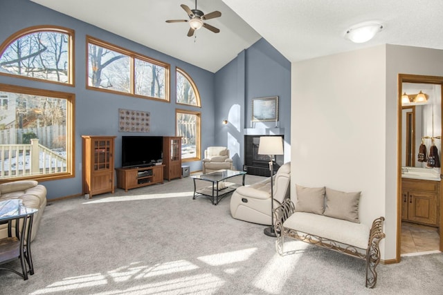 carpeted living room with a healthy amount of sunlight, high vaulted ceiling, and ceiling fan