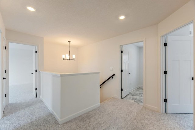 hallway featuring an inviting chandelier and light colored carpet