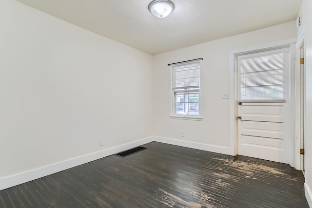 spare room featuring a textured ceiling and dark wood-type flooring