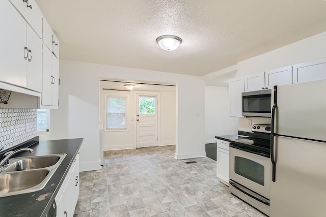 kitchen featuring appliances with stainless steel finishes, white cabinets, a textured ceiling, and sink