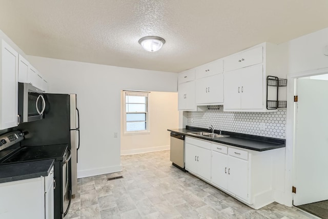 kitchen featuring appliances with stainless steel finishes, a textured ceiling, sink, white cabinetry, and backsplash