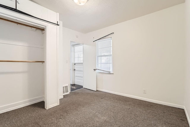 unfurnished bedroom with dark carpet, a closet, and a textured ceiling