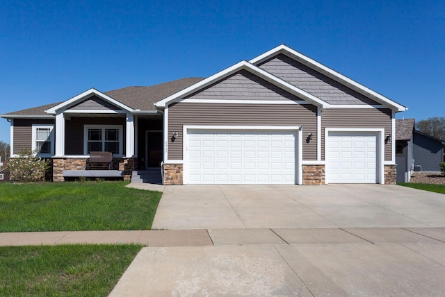 craftsman-style house with an attached garage, concrete driveway, a front lawn, and stone siding