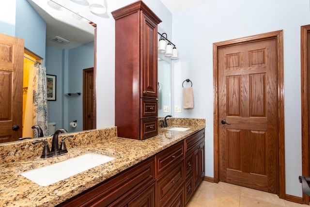 bathroom featuring toilet, tile patterned flooring, double vanity, and a sink