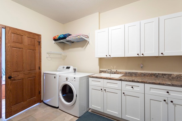 clothes washing area with washing machine and clothes dryer, light wood finished floors, cabinet space, and a sink