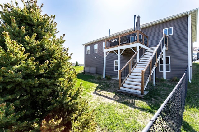 rear view of property with a yard, a deck, stairway, and fence