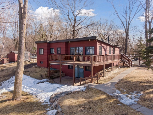 view of front facade with a deck, a patio, an outdoor structure, and stairs