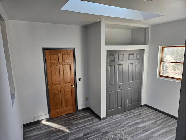 unfurnished bedroom with a skylight, dark wood-type flooring, and a closet