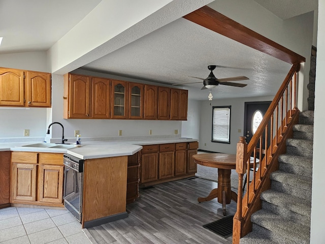 kitchen with black dishwasher, sink, ceiling fan, light hardwood / wood-style floors, and a textured ceiling