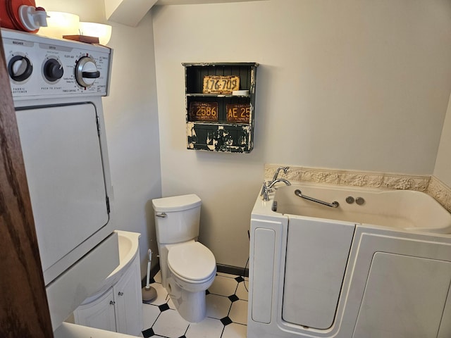 bathroom with toilet, washer / dryer, and a bathing tub