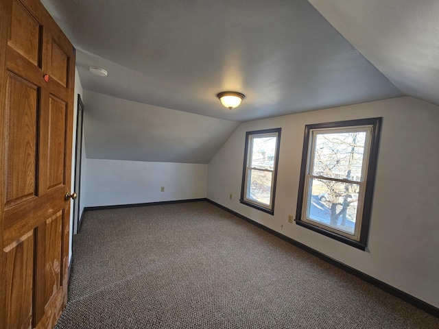 bonus room featuring vaulted ceiling and dark carpet